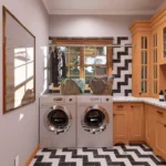A functional cottage utility room featuring white laundry machines, granite countertops, and light oak cabinetry. The space is accented by a striking black-and-white herringbone backsplash and floor tile, with a window providing natural light